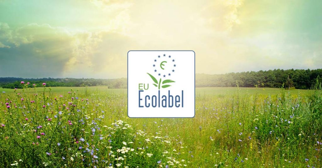 Símbolo de la Etiqueta Ecológica y, de fondo, un campo verde y un cielo radiante.