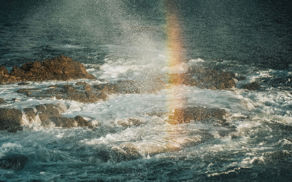 Arco iris sobre la orilla del mar bajo las nubes